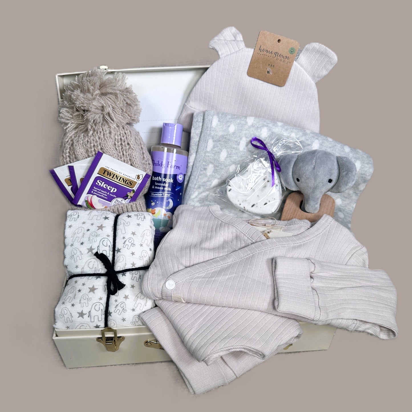 Baby gift basket with clothes, toys, and products on a beige background