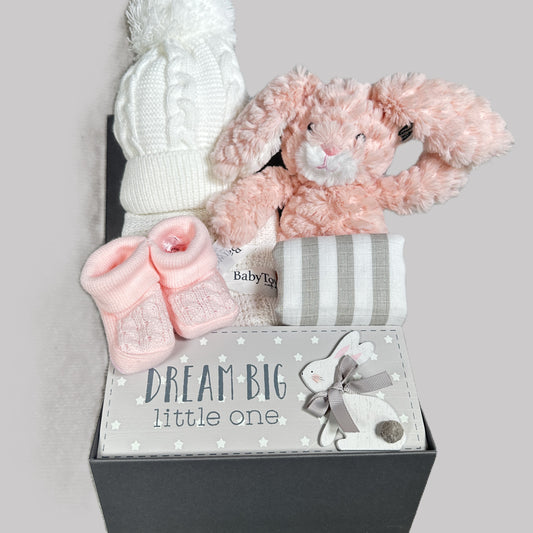 Baby gift set with pink bunny, pink, booties, and white cellular baby blanket, muslin and baby pompom hat in a baby keepsake box with 'Dream Big little one' text.