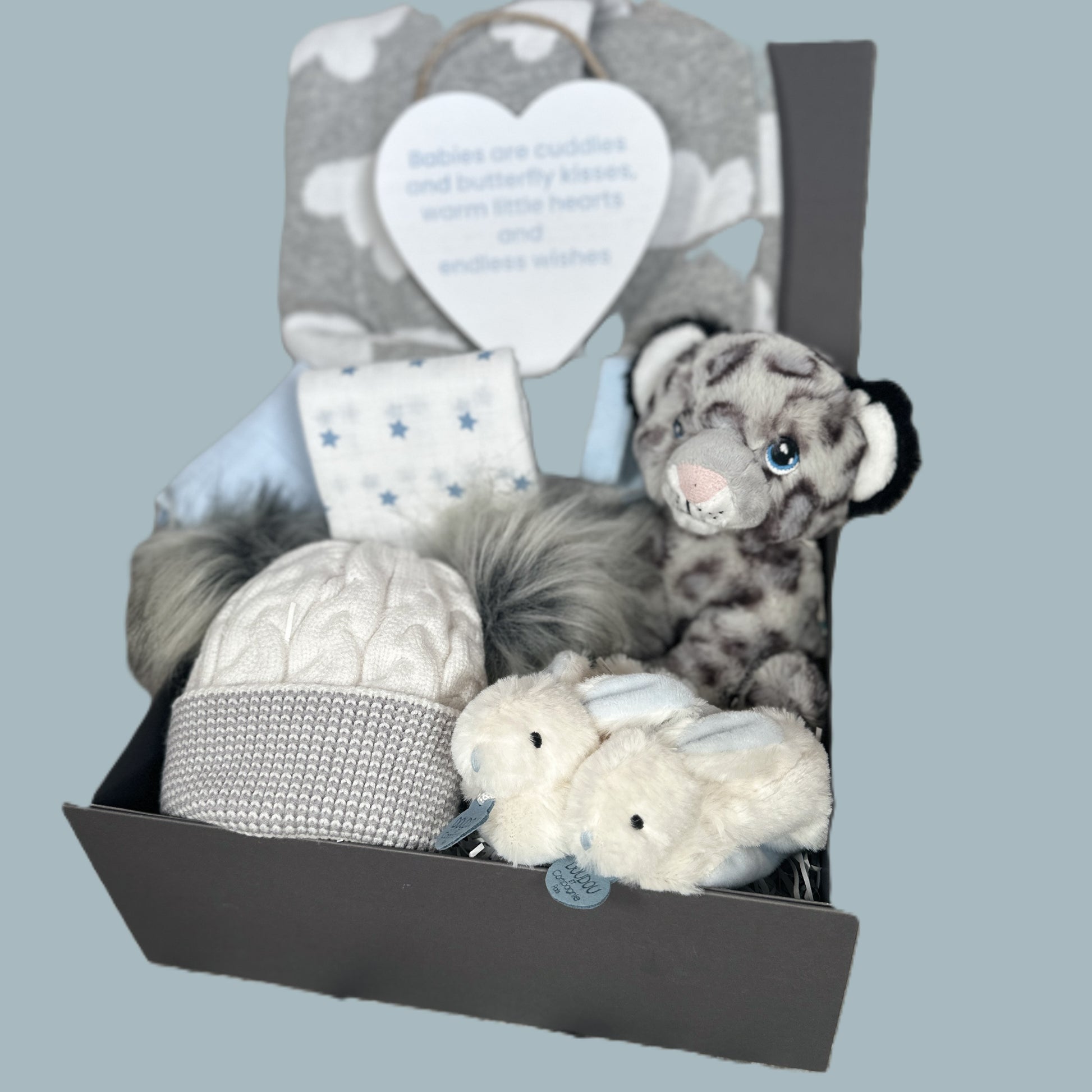 Baby boy hamper with soft toys and baby items in a box on a light blue background