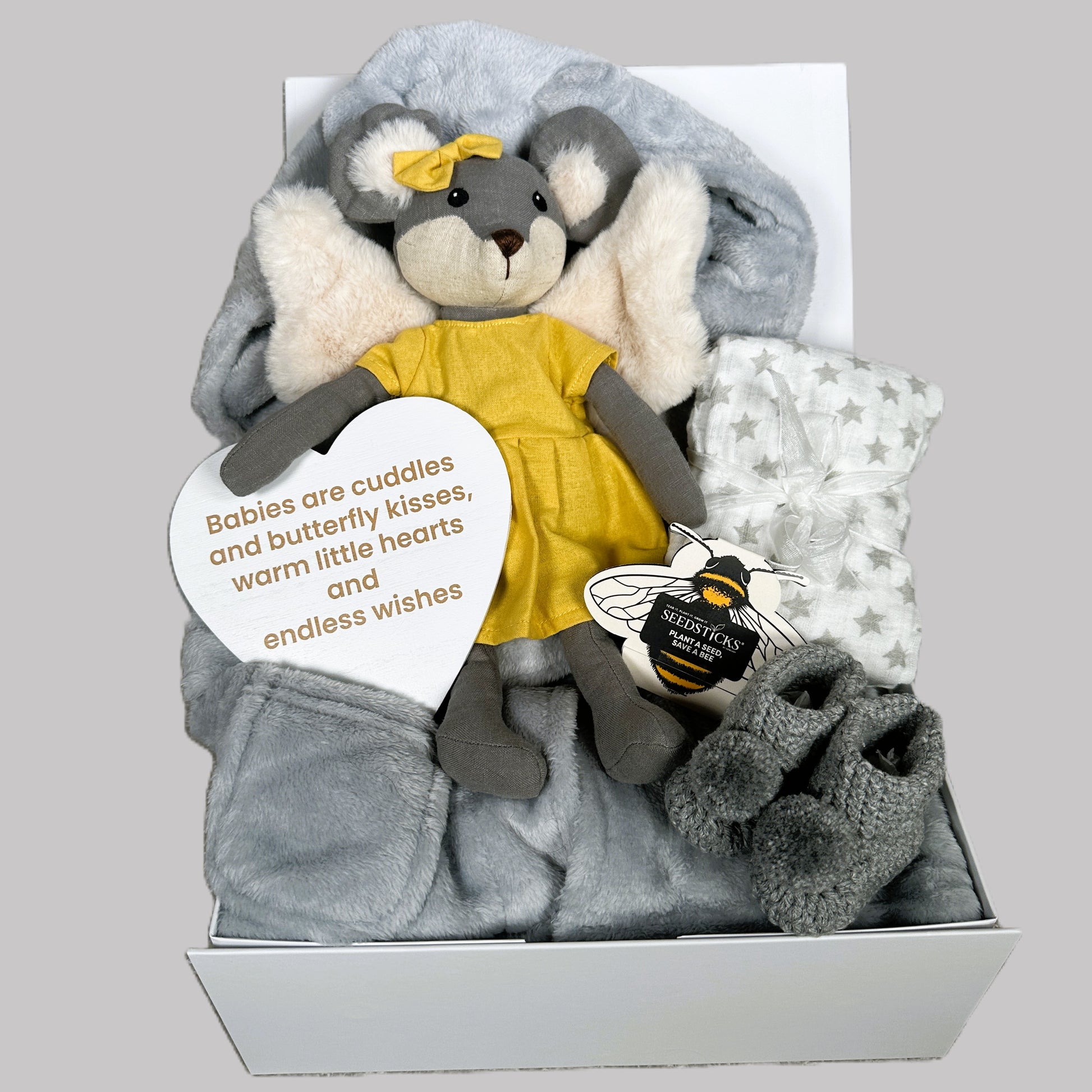 New baby girl gift set with plush toy, blanket, and booties on a grey background