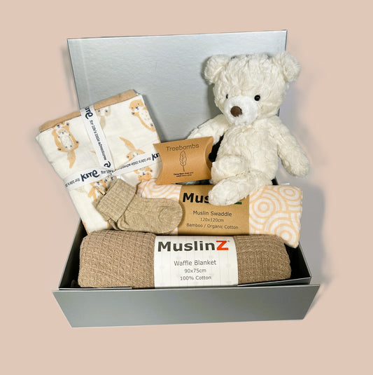 New baby girl hamper in a sliver coloured baby keepsake box which contains a Mary Meyer cream teddy bear, a muslins baby swaddle and baby blanket.  3 organic cotton baby muslins, one with an otter print.