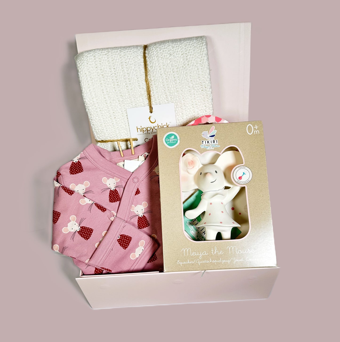 A new new parents hamper in a magnetic baby keepsake case containing an organic baby romper with lovely mouse print, a Tikiri natural rubber teething toy and a white Hippychick cotton cellular baby blanket.