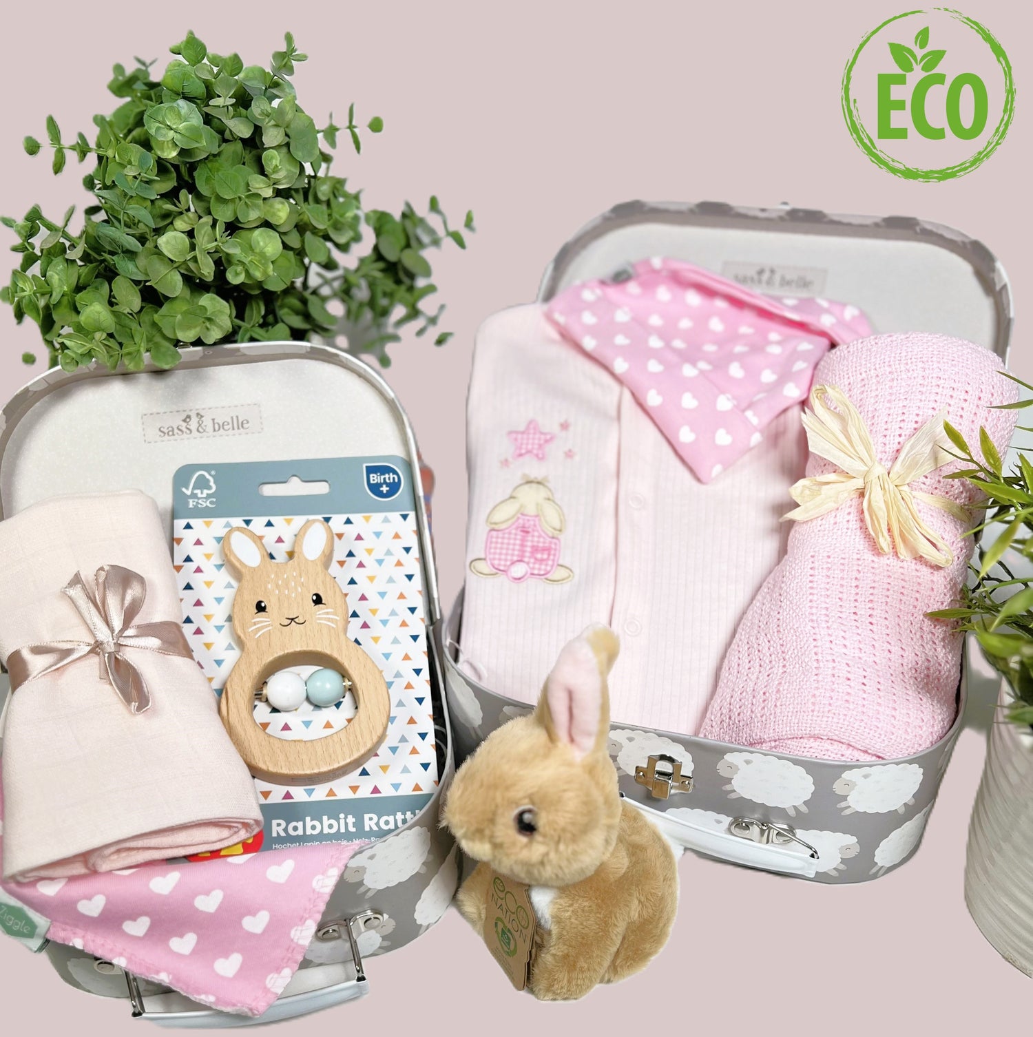 Eco Friendly pink and white baby girl gift contains a pink cotton ribbed baby sleepsuit wit an applique rabbit looking at a star, a pink cotton cellular baby blanket,a FSC wooden bunny shaped baby rattle, an eco friendly bunny soft toy, a coton baby bib and matching baby knot hat and 2 baby keepsake cases.