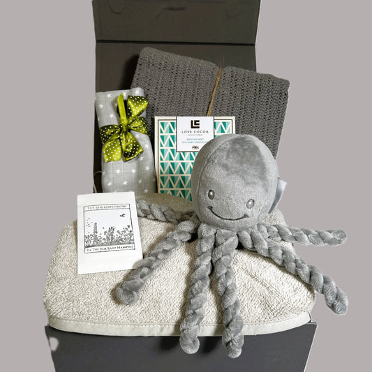 Neutral newborn baby gift hamper containing a PUIpui octopus soft baby toy, a cotton cellular baby blanket, a grey cotton hooded baby towel, a bar of Love Cocoa chocolate and a grey muslin square.