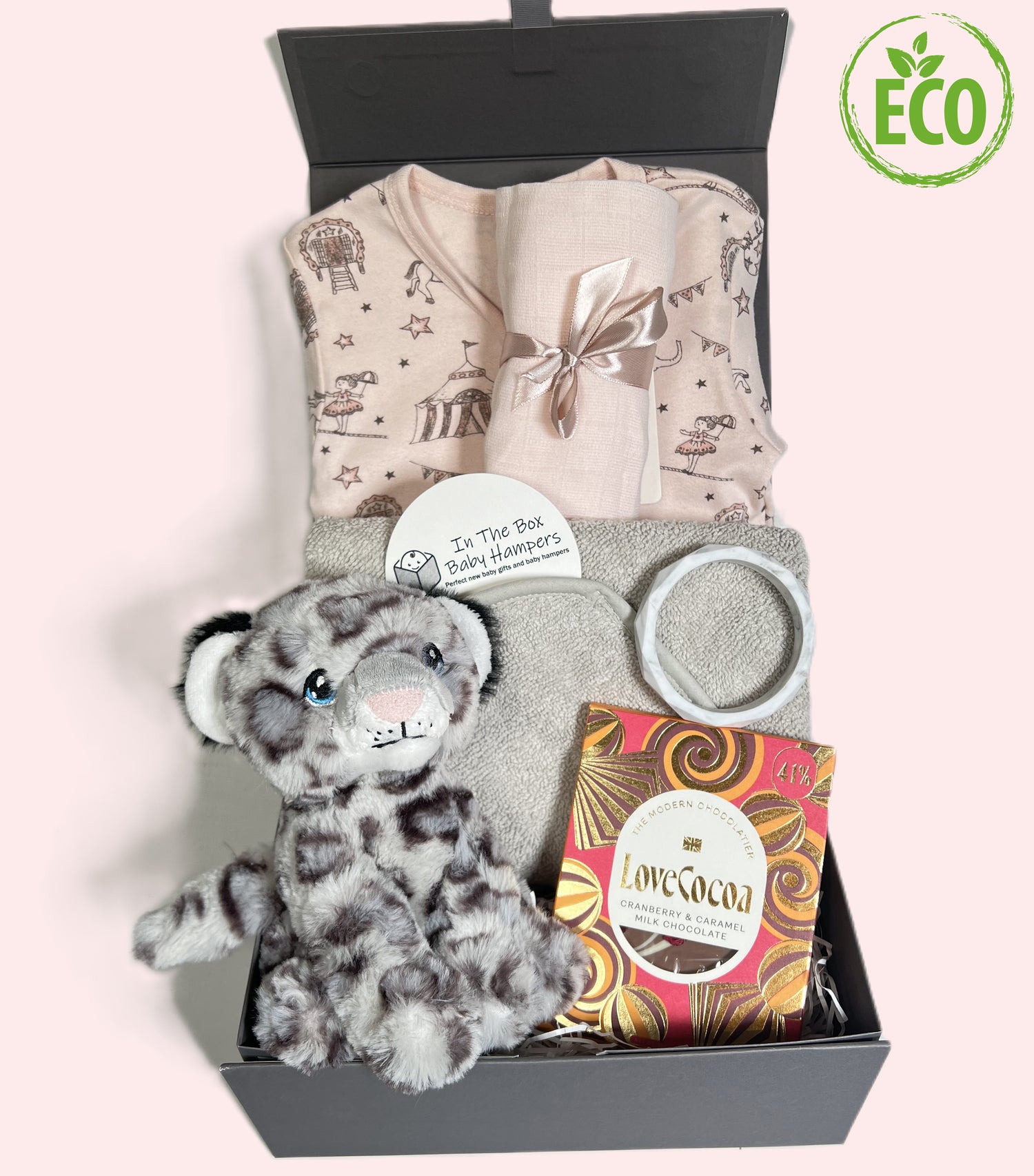 New Baby girl gift box containing a pink organic cotton zipped baby sleepsuit with circus print, a grey hooded baby towel, a Keeleco snow leopard soft baby toy, a silicone teething bracelet and a bar of Love Cocoa chocolate