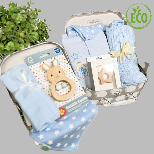 Two baby gift case containing a blue cotton cellular baby blanket, a blue muslinsqaure, a FSC wooden baby rattle, a Bambino wooden teething star, a baby knot hat and matching blue and white dribble bib and cotton blue ribbed sleepsuit with applique bunny motif.