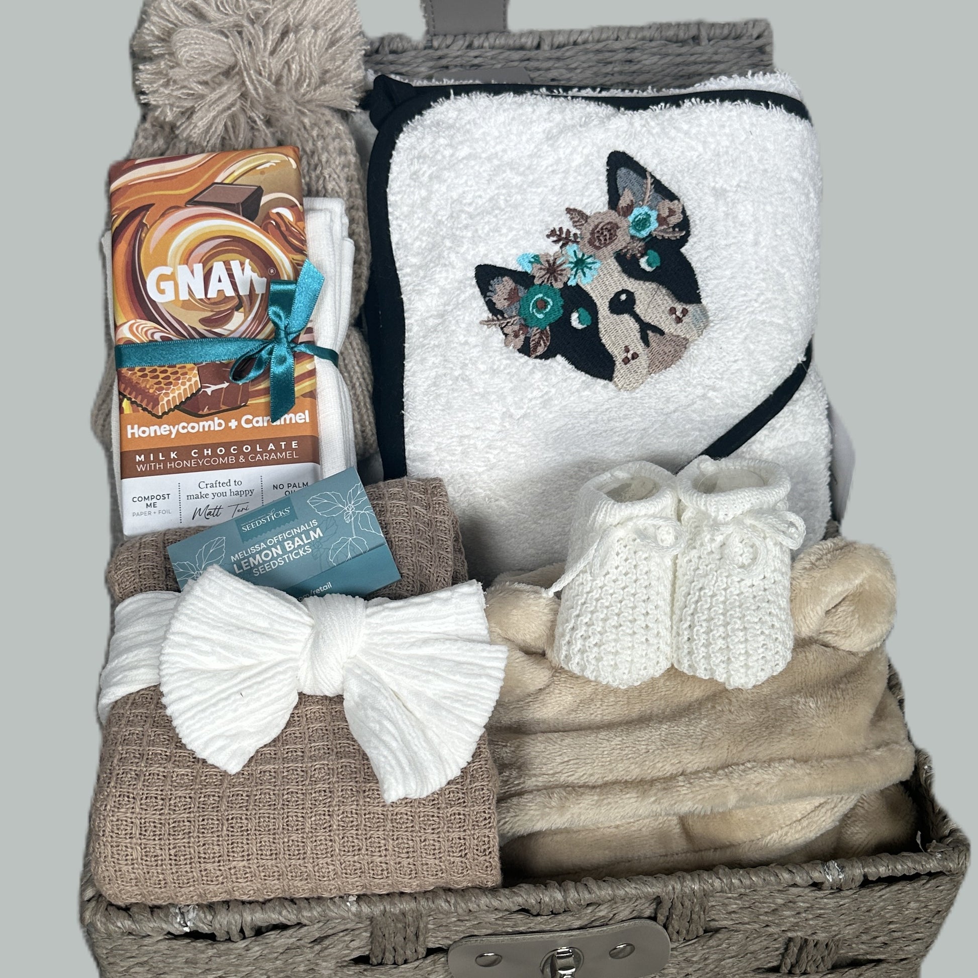 New Baby Girl hamper with bulldog embroidered baby hooded towel, blanket, and chocolate bar on a gray background