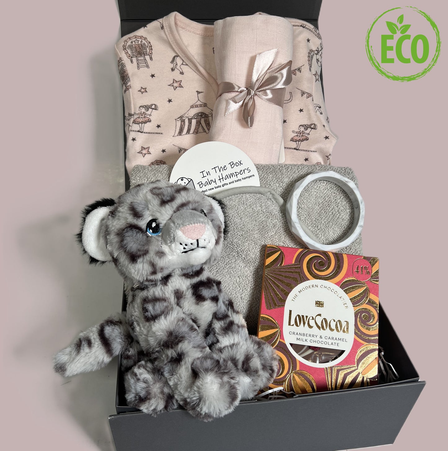 New Baby girl gift box containing a pink organic cotton zipped baby sleepsuit with circus print, a grey hooded baby towel, a Keeleco snow leopard soft baby toy, a silicone teething bracelet and a bar of Love Cocoa chocolate