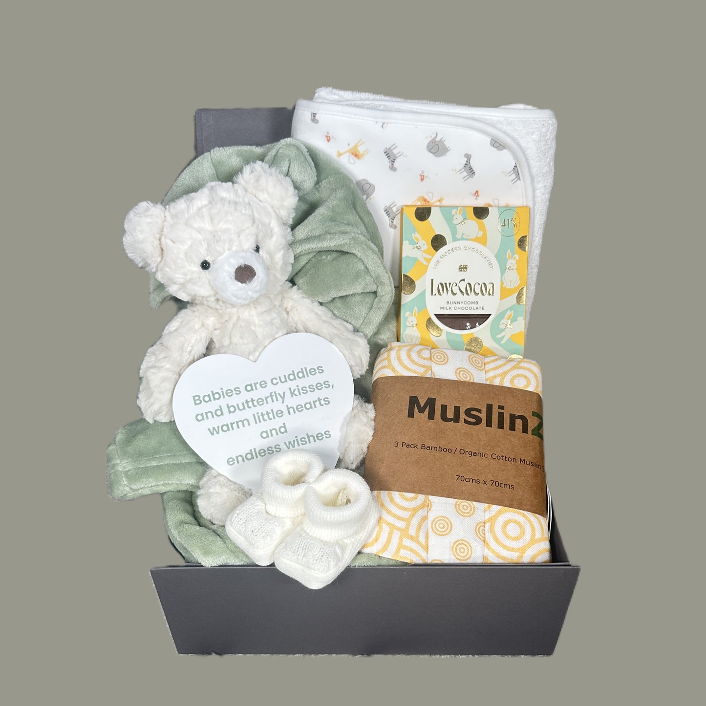 Baby gift set with teddy bear, blankets, and other items on a gray background