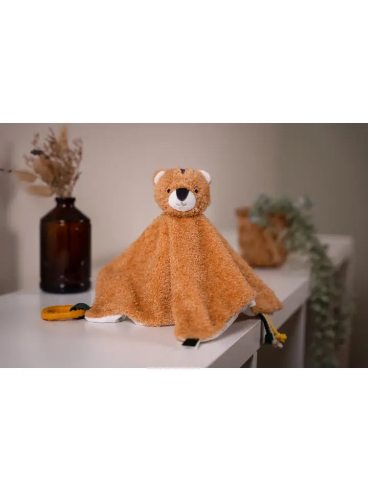 Tiger baby comforter on a white surface with decorative items in the background.