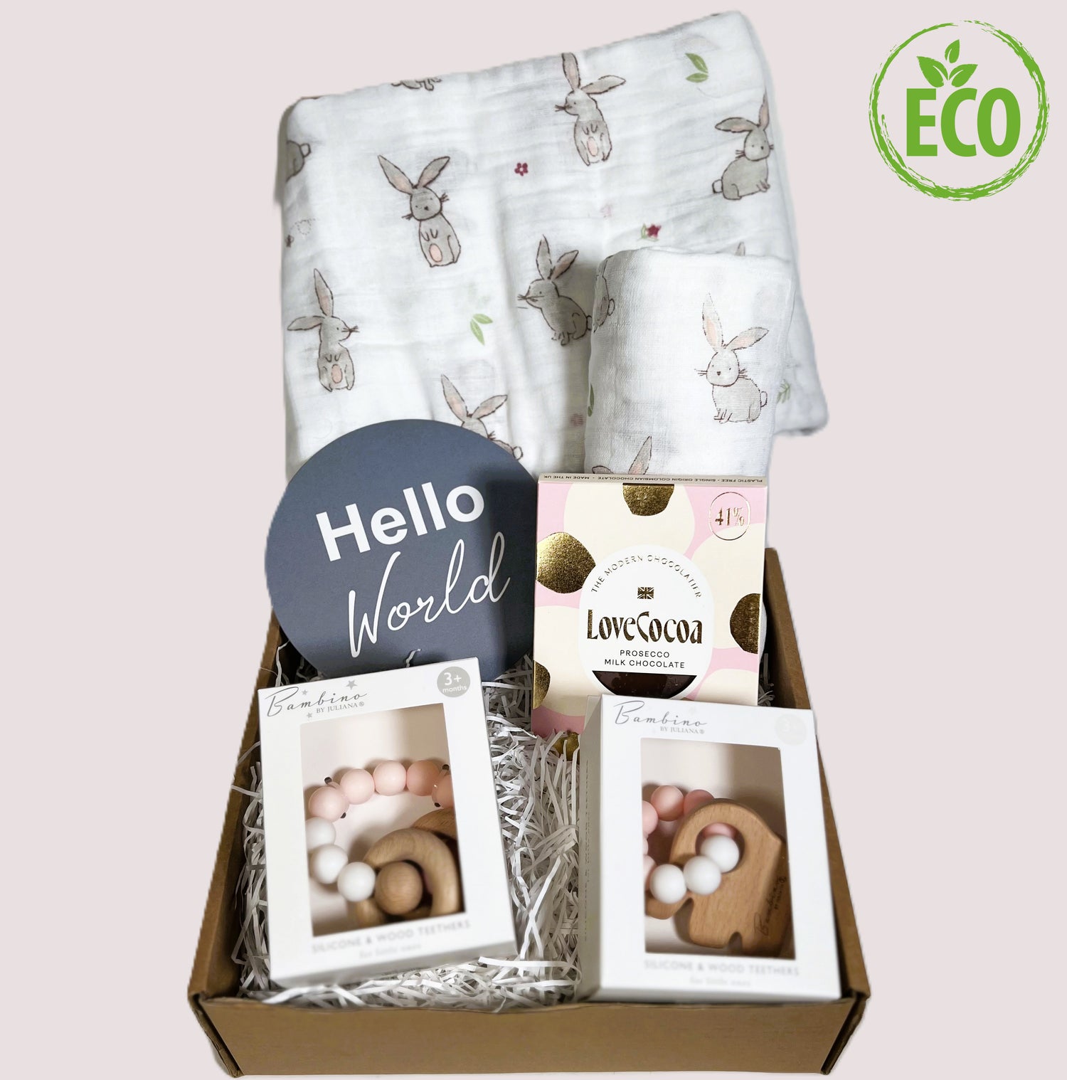 New twin baby girls gift hamper with 2 large muslins with a bunny print and 2 pink and white silicone and wood teething toys, a bar of Prosecco flavoured Love Cocoa chocolate and a baby photography plaque which reads "hello world"