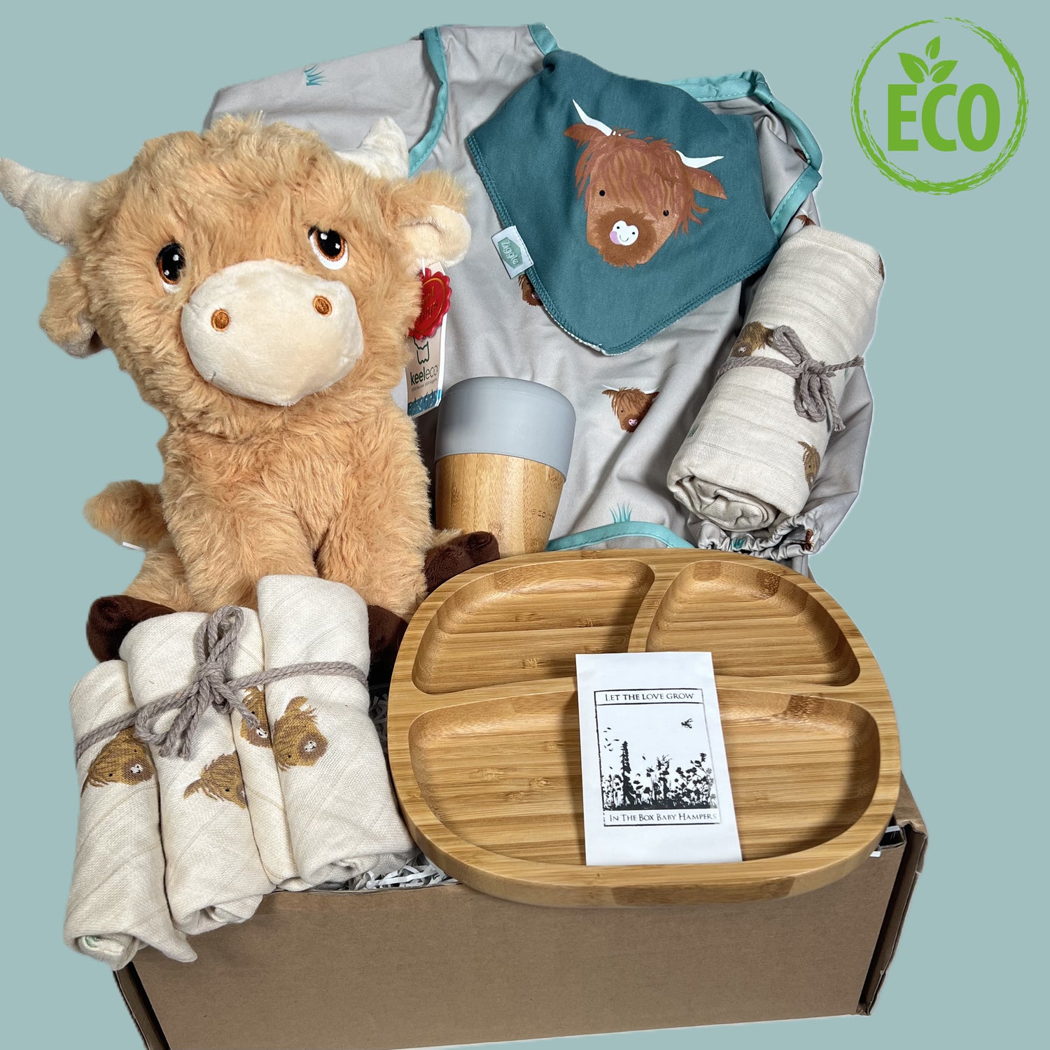 New baby gift hamper includes a 25 cms Keeleco highland cow soft toy, an Eco Rascals bamboo baby plate and sippy cup, a highland cow print baby weaning coverall, matching cotton baby bib, face cloths and a large highland cow print muslin square.