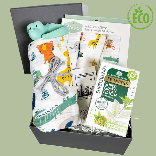 A unisex new baby gift hamper in a greay gift box containing a large swaddle balnket in a jungle print with a set of three smaller matching muslins squares, a Tikiri natural rubber crocodile baby teether, a pcket of Match teabags and a pack of wild flower seeds for the birds and butterflies.