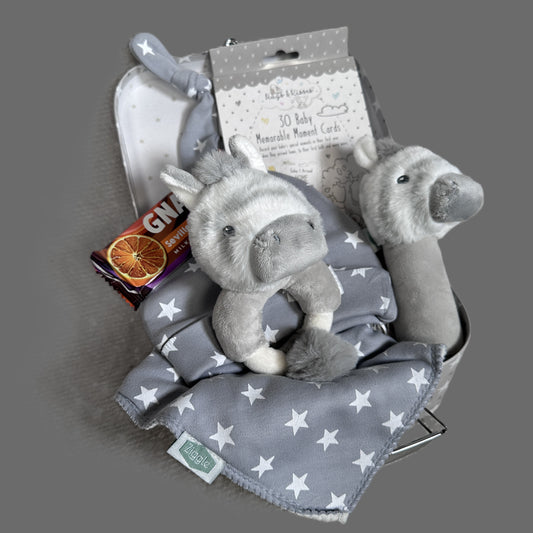 Unisex baby hamper grey and white with Zebra  plush toys, baby hat, and a chocolate bar on a grey background