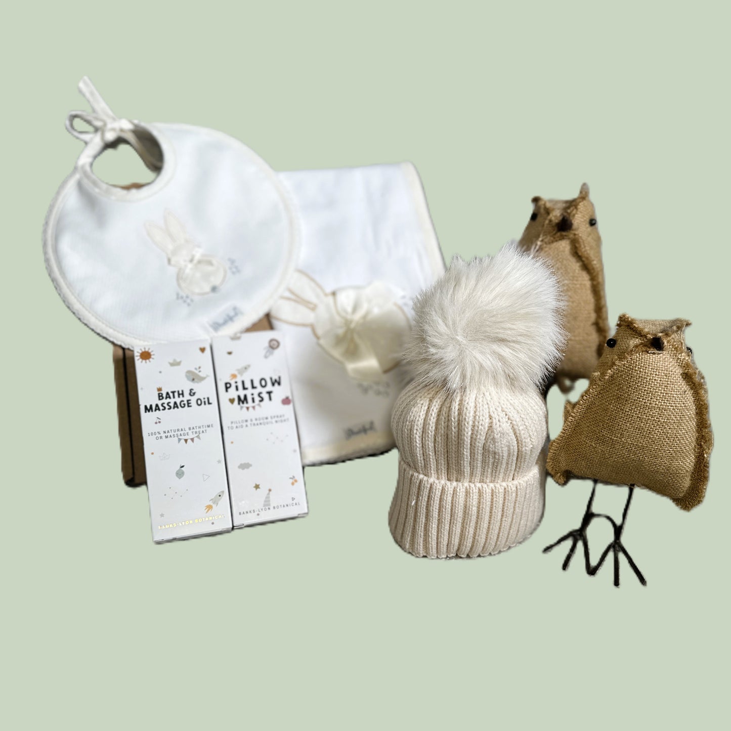 Baby gift hamper with hat, bib, baby pillow mist and baby massage oil on a light green background