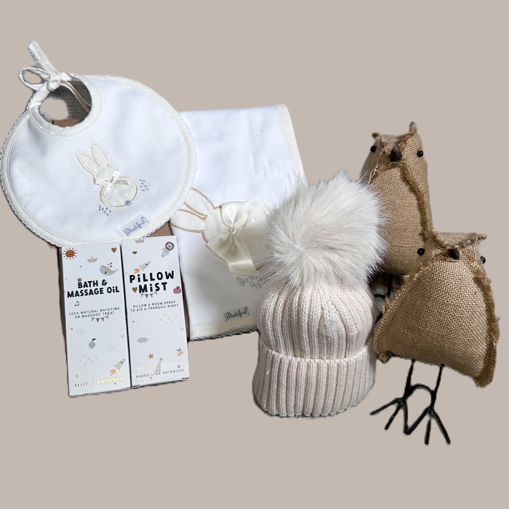 neutral new baby hamper with baby pillow mist and baby massage oil. on a beige background