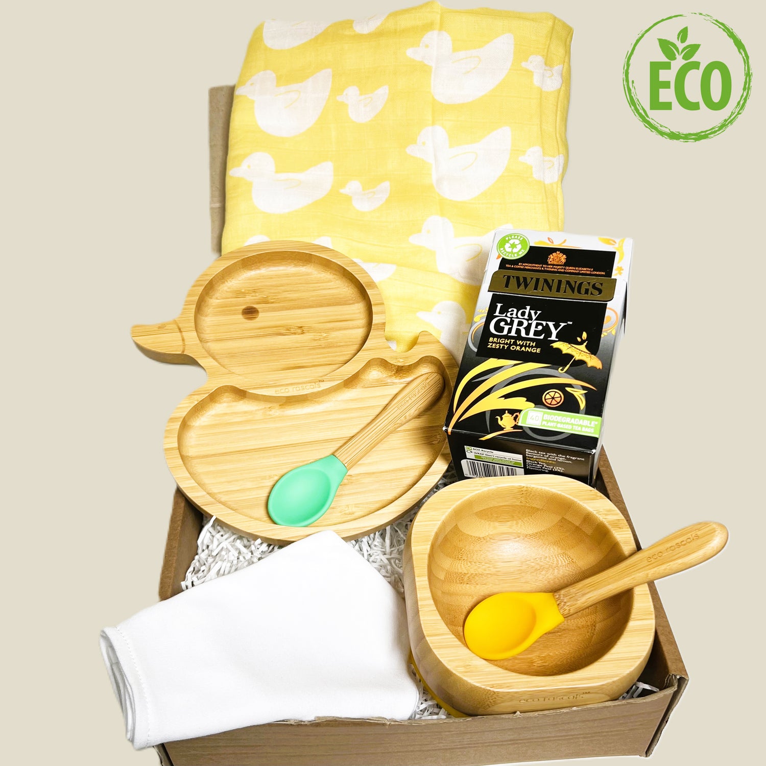 Baby weaning gift with a bamboo duck shaped plate and a bamboo bowl both with silicone and bamboo baby spoons, a large yellow and white bamboo baby muslin and a packet of Earl grey Twinings teabags