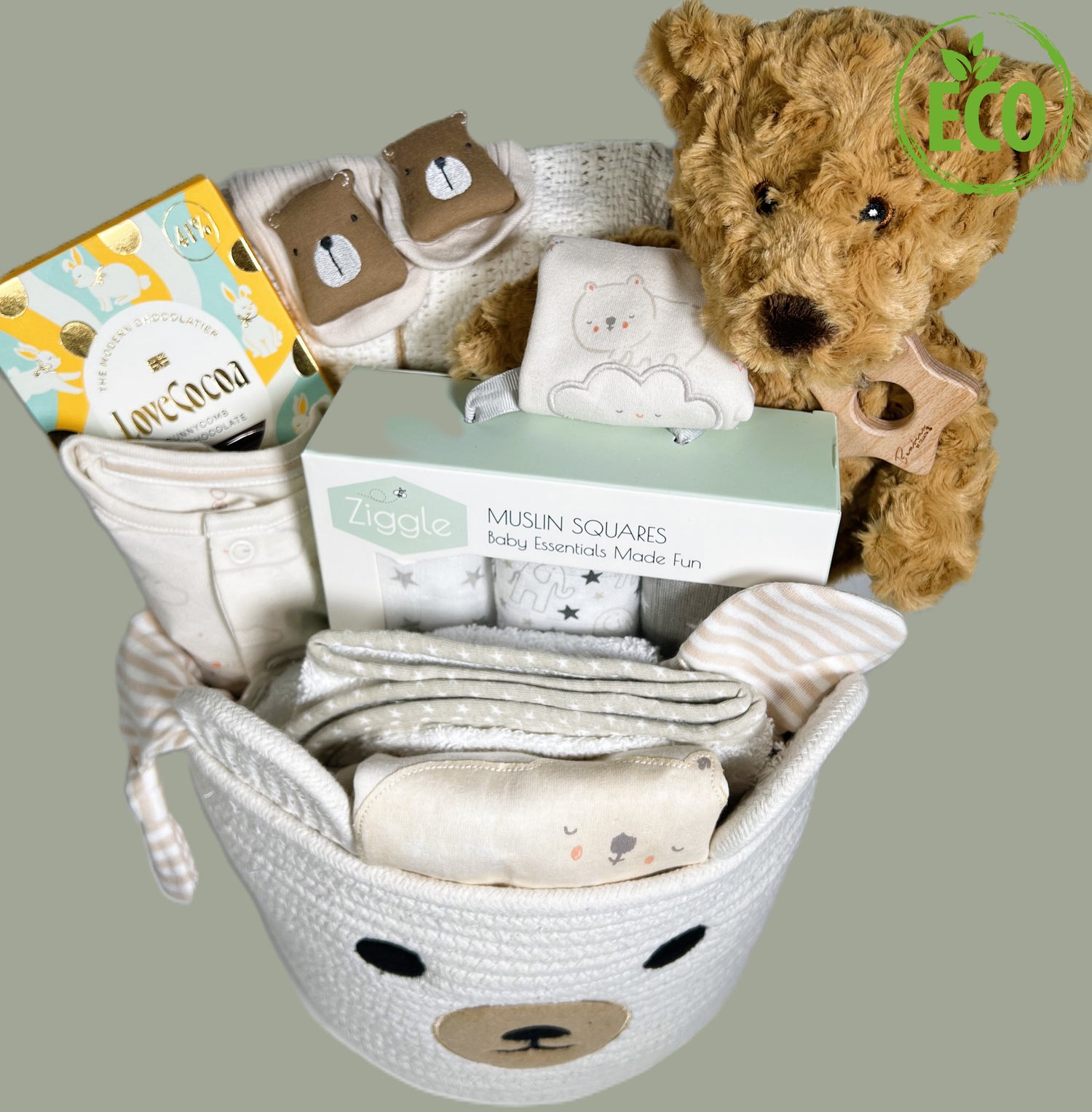 Baby Hamper gift in a rope bear storage caddy containing a eco friendly bear soft toy, a cotton baby layette set, a hooded baby towel, a white cotton cellular baby blanket and treats for the new mummy.