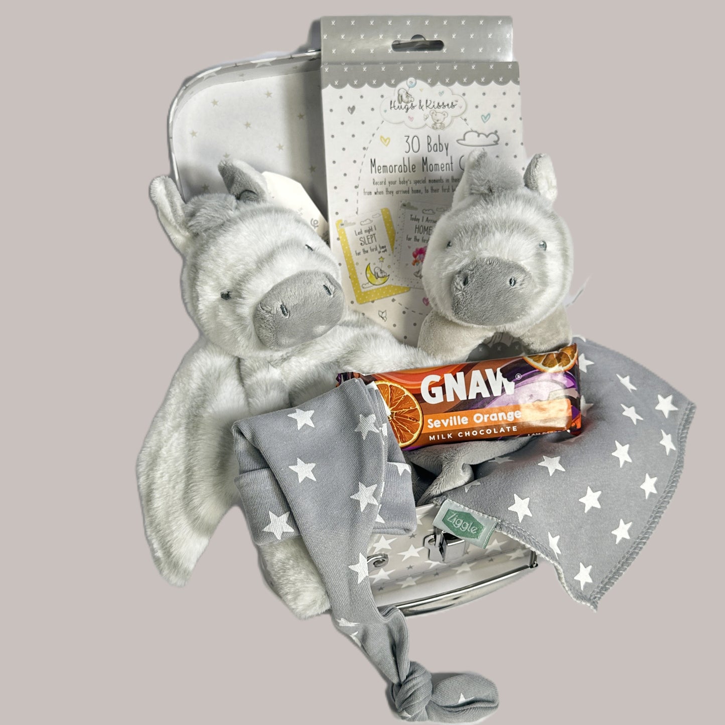 A baby keepsake case with two Keeleco zebra baby toy, a bar of seville orange Gnaw chocolate, a bay knot hat and bib.