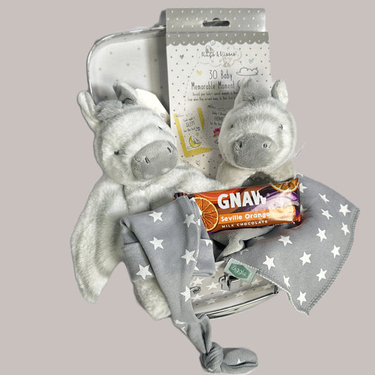 A baby keepsake case with two Keeleco zebra baby toy, a bar of seville orange Gnaw chocolate, a bay knot hat and bib.