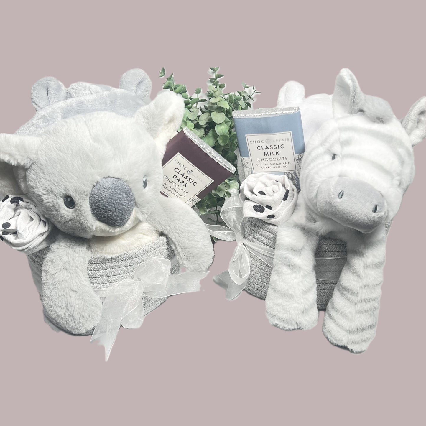 Unisex grey and white new baby hamper gifts in a cotton rope storage caddy in grey tied with a white organza ribbon, a grey and white koala bear or Zebra baby soft toy a bar of chocolate , a grey or white dressing gown and a black and white baby muslin.