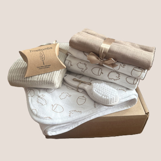 Baby gift set with blanket, swaddle, and baby hairbrush in a box on a light background