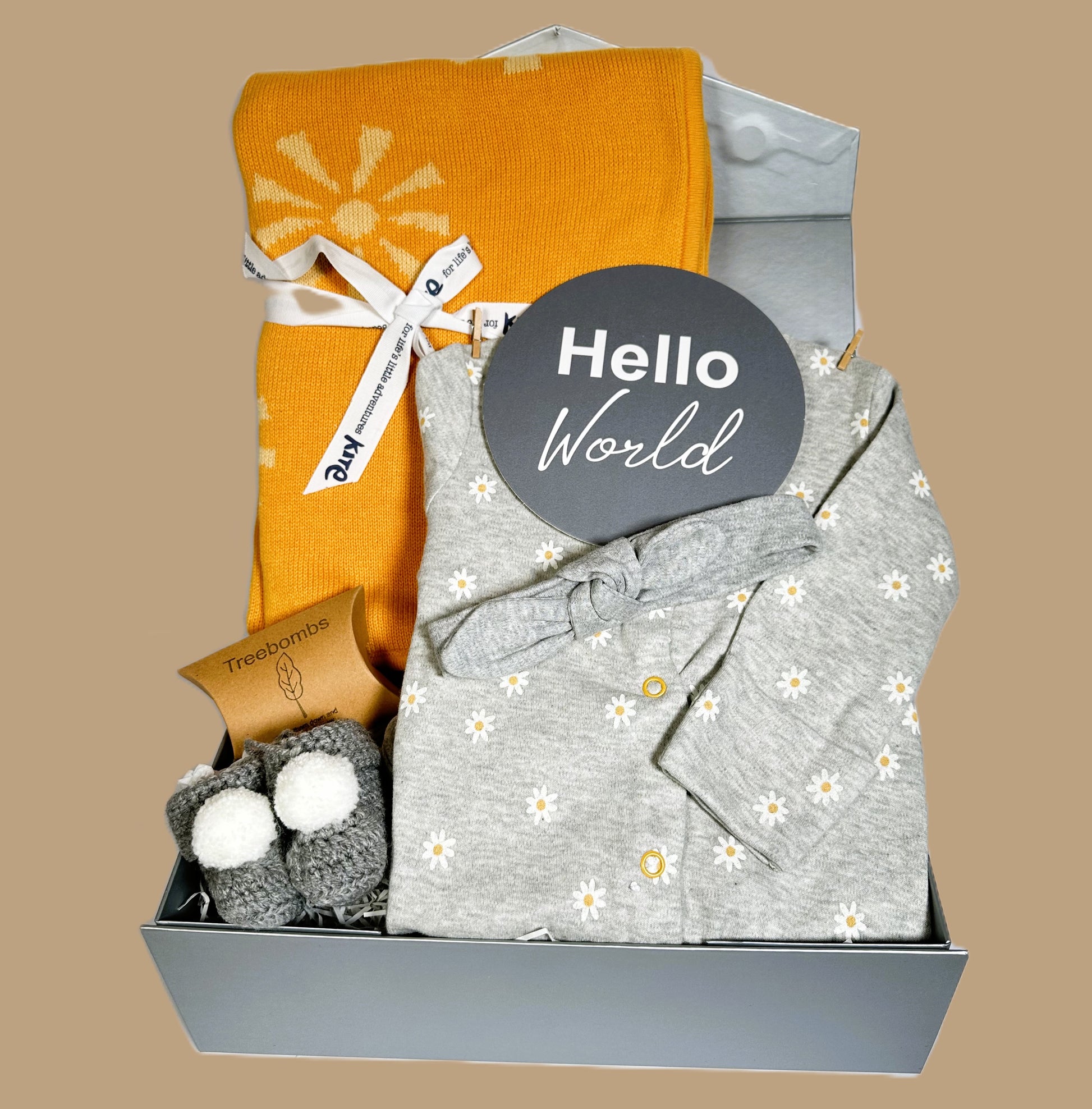 New baby girl hamper gift box containing a cotton baby sleepsuit with a white and yellow daisy print and a cotton baby headband. An Organic cotton baby blanket with a sunshine print.