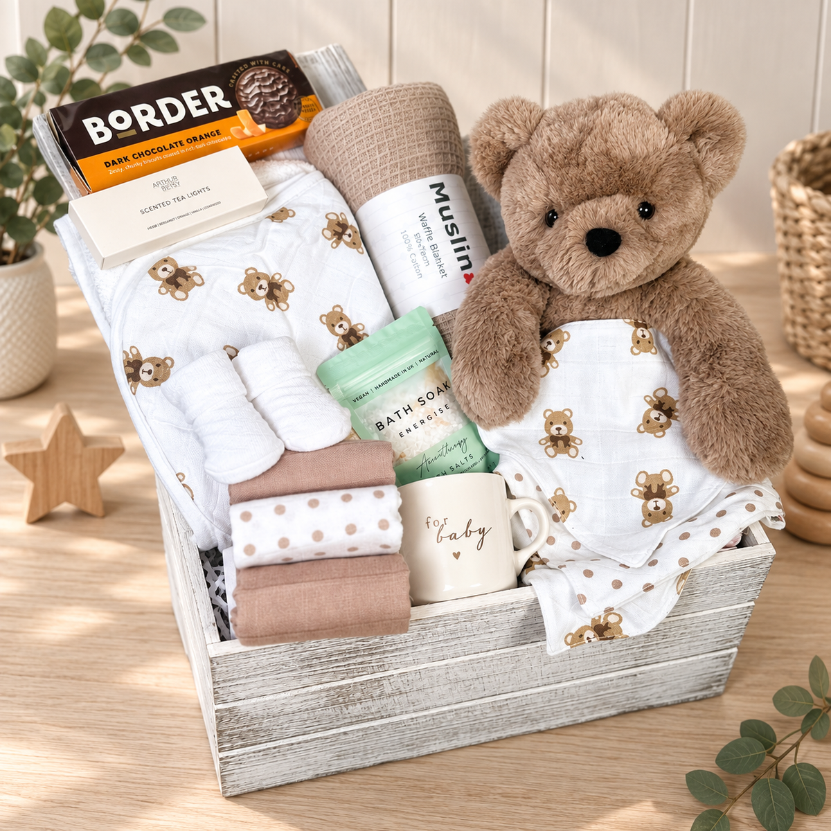 A neutral baby hamper in a wooden baby keepsake box with bear print baby bibs and a cotton hooded baby towel, brown bear, taupe cotton baby blanket , muslins, ceramic baby cup, baby socks, bath salt an treats for mummy