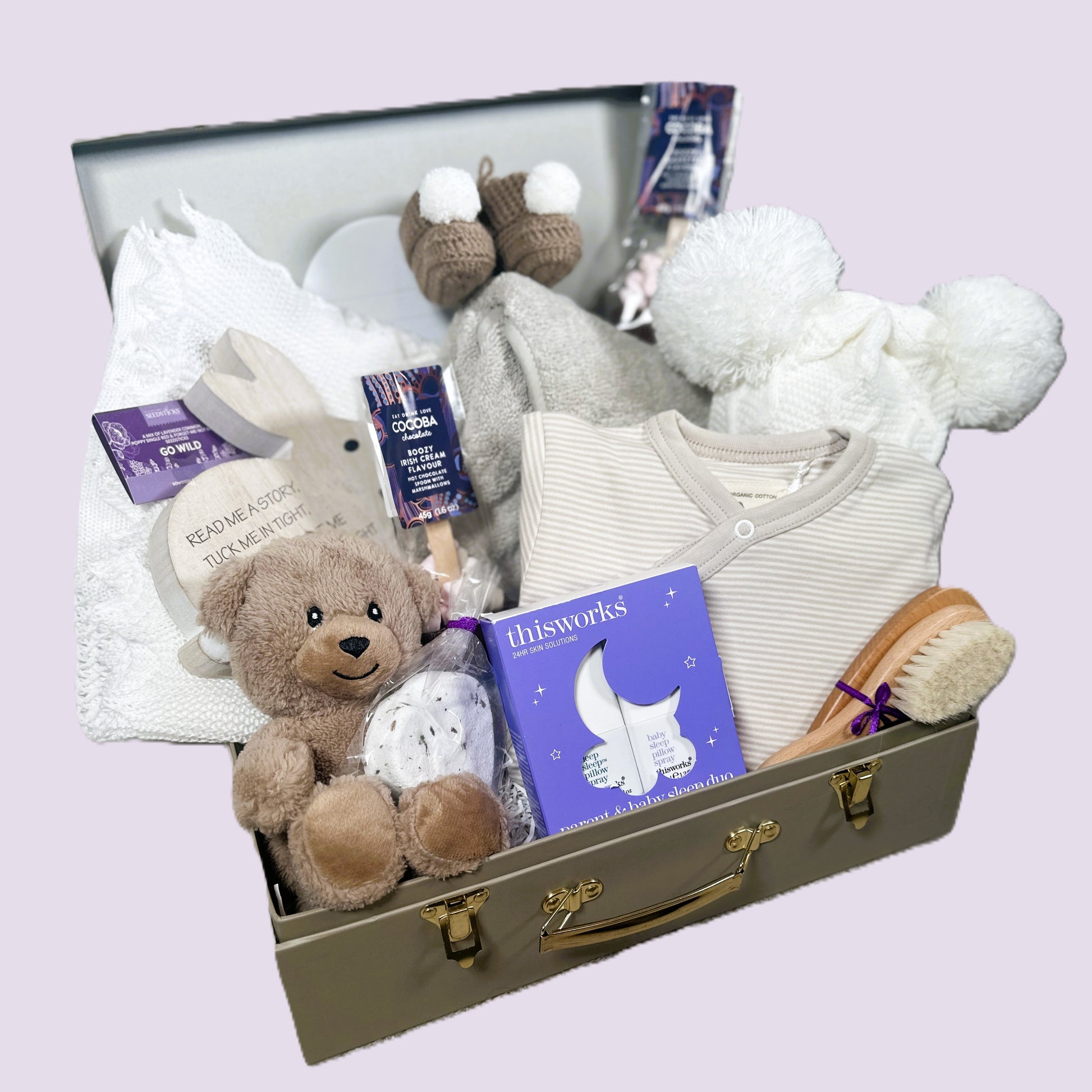 new baby hamper with baby clothes and baby blanket and chocolate and baby hairbrush.