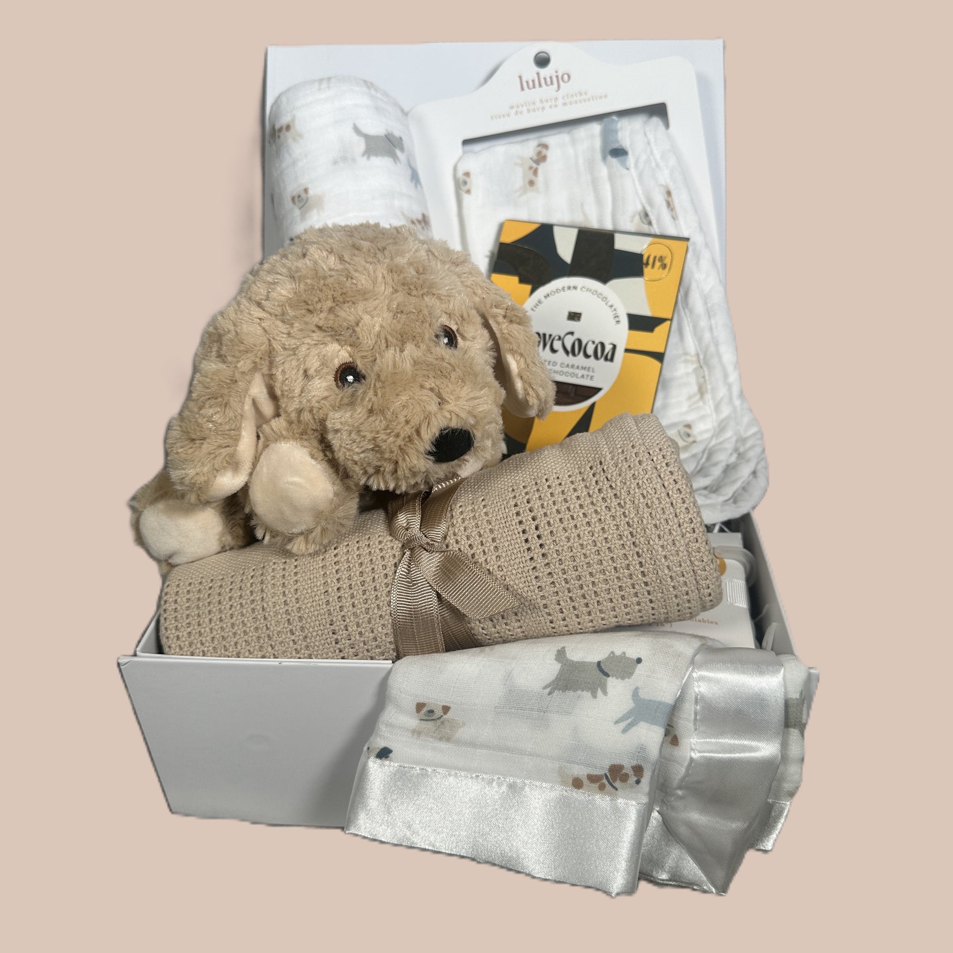 The Puppy Love Baby Essentials Hamper  full of babby blankets and burp cloths.