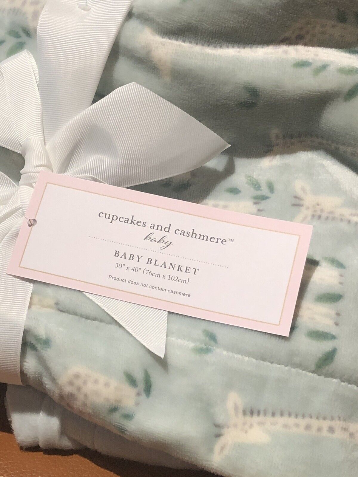 Baby blanket  in green and cream  with a visible 'Cupcakes and Cashmere' tag on a soft background