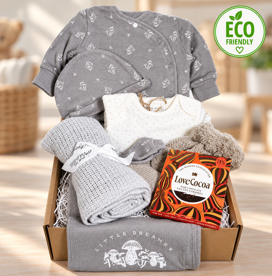 Unisex New baby gift with an organic cotton layette set in taupe and white, the bib reads "little and loved" in white print and the suit has a small repeated toadstool pattern, a grey cellular baby blanket, a biscuit coloured baby pompom hat
