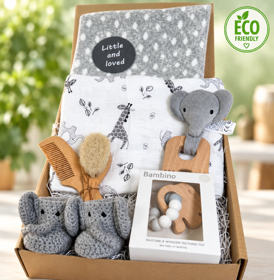 A new  parents andbaby hamper full of elephant baby essentials such aa a large white baby muslin with grey elephant and zebra print. Two elephant baby teething toys. A pair of crocheted baby booties with an elephant face, a grey organic cotton baby blanket and a baby hairbrush and comb set.