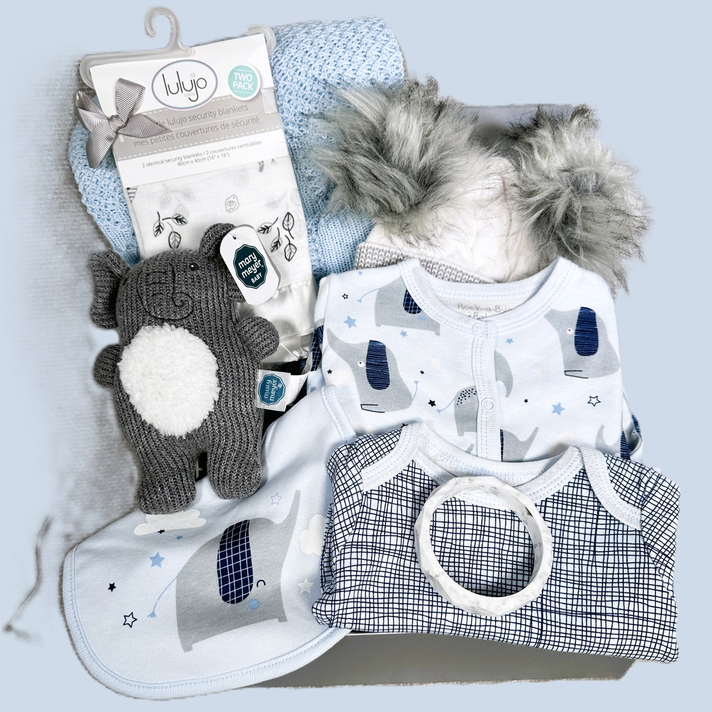 blue elephant themed baby hamper with baby clothes, baby rattle baby blanket and hat.