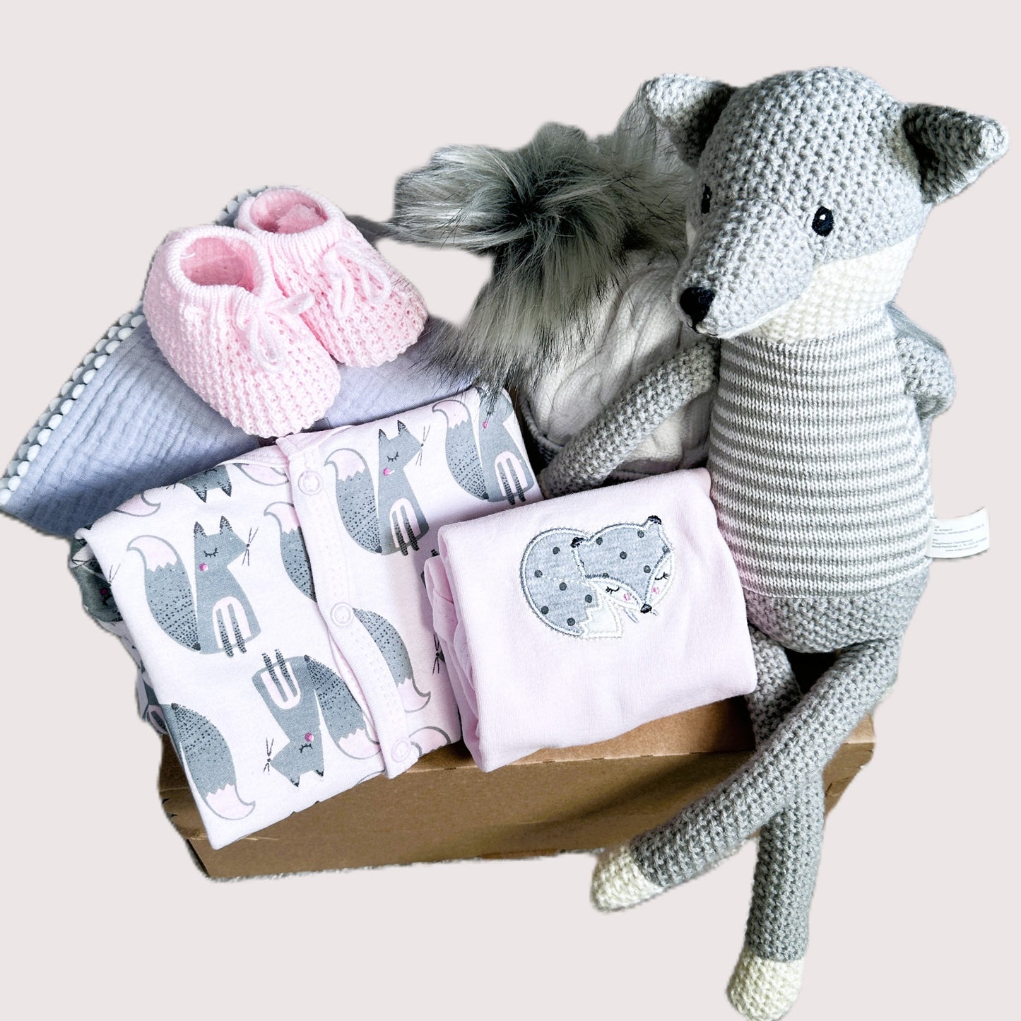 BABY HAMPER with baby items including a knitted fox toy, pink booties, and baby blankets with fox print.