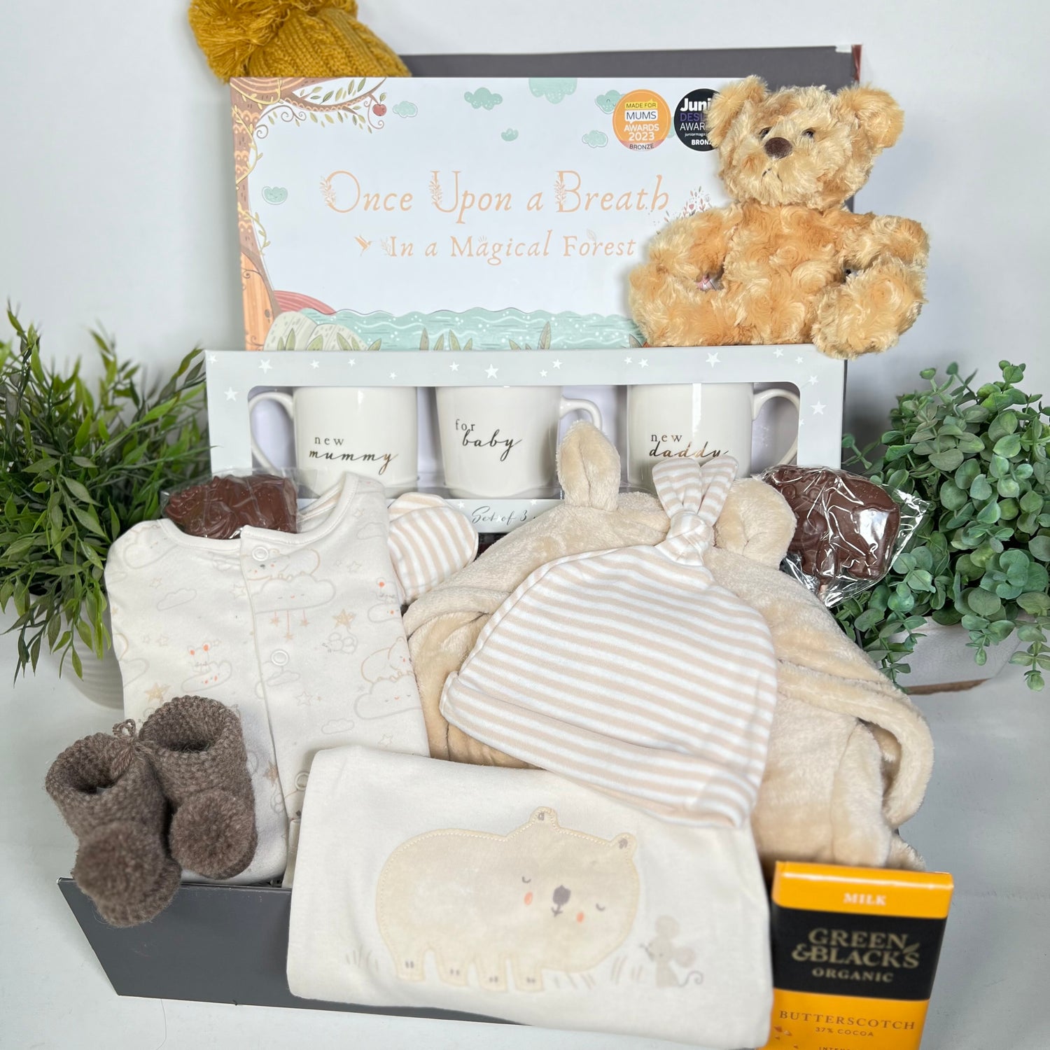 Neutral new parents gift hamper box, containg chine new mummy and daddy mugs, a flip and flow mindelfullness gift for children, a baby dressing gown, cotton baby clothes, Merino baby pompom booties.