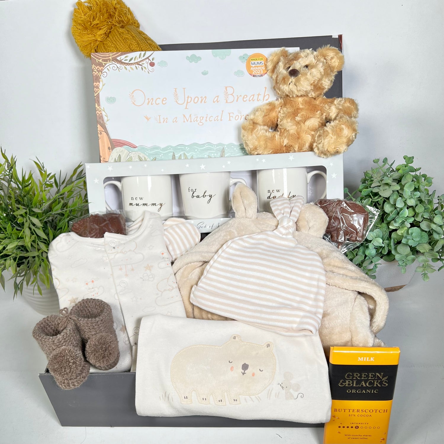 Neutral new parents gift hamper box, containg chine new mummy and daddy mugs, a flip and flow mindelfullness gift for children, a baby dressing gown, cotton baby clothes, Merino baby pompom booties.