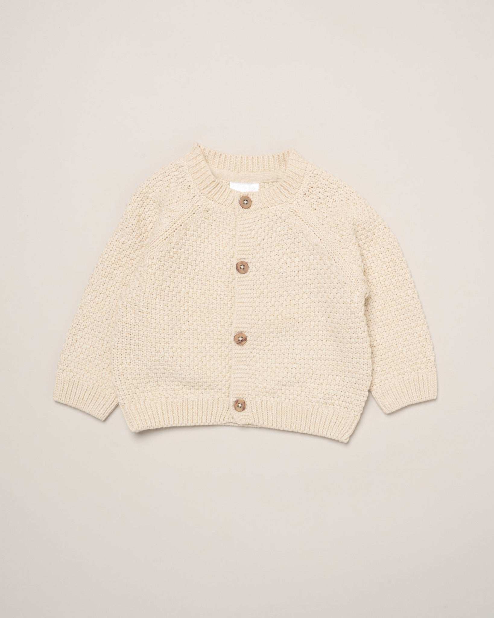 cream cotton baby cardigan with button and embroidered text on the back