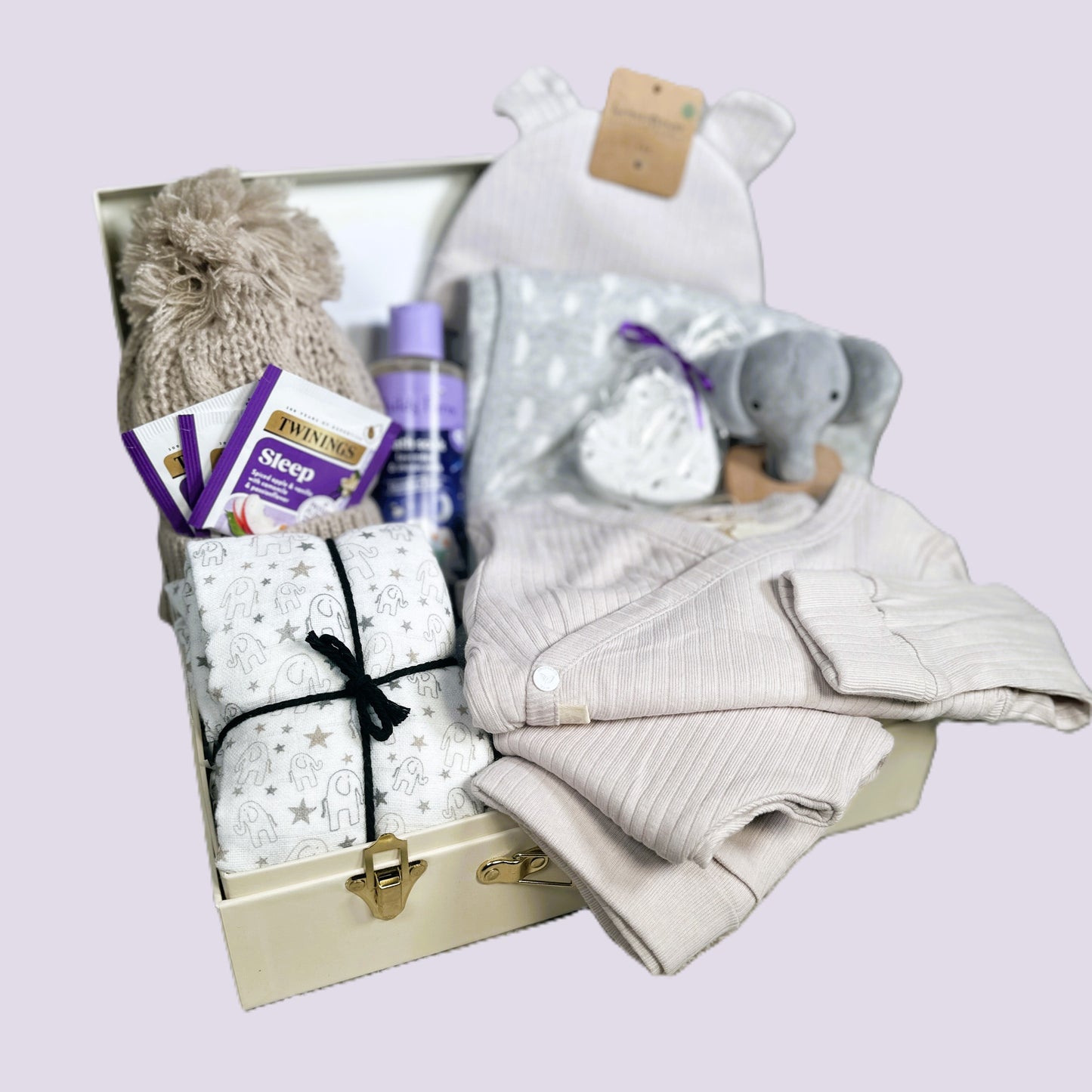 new baby gift hamper  with clothes, toys, and products on a light purple background