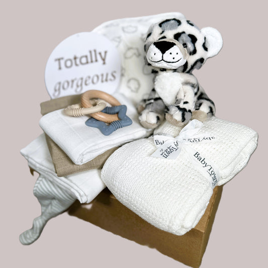 Baby gift set with plush toy, blanket, and rattle on a beige background
