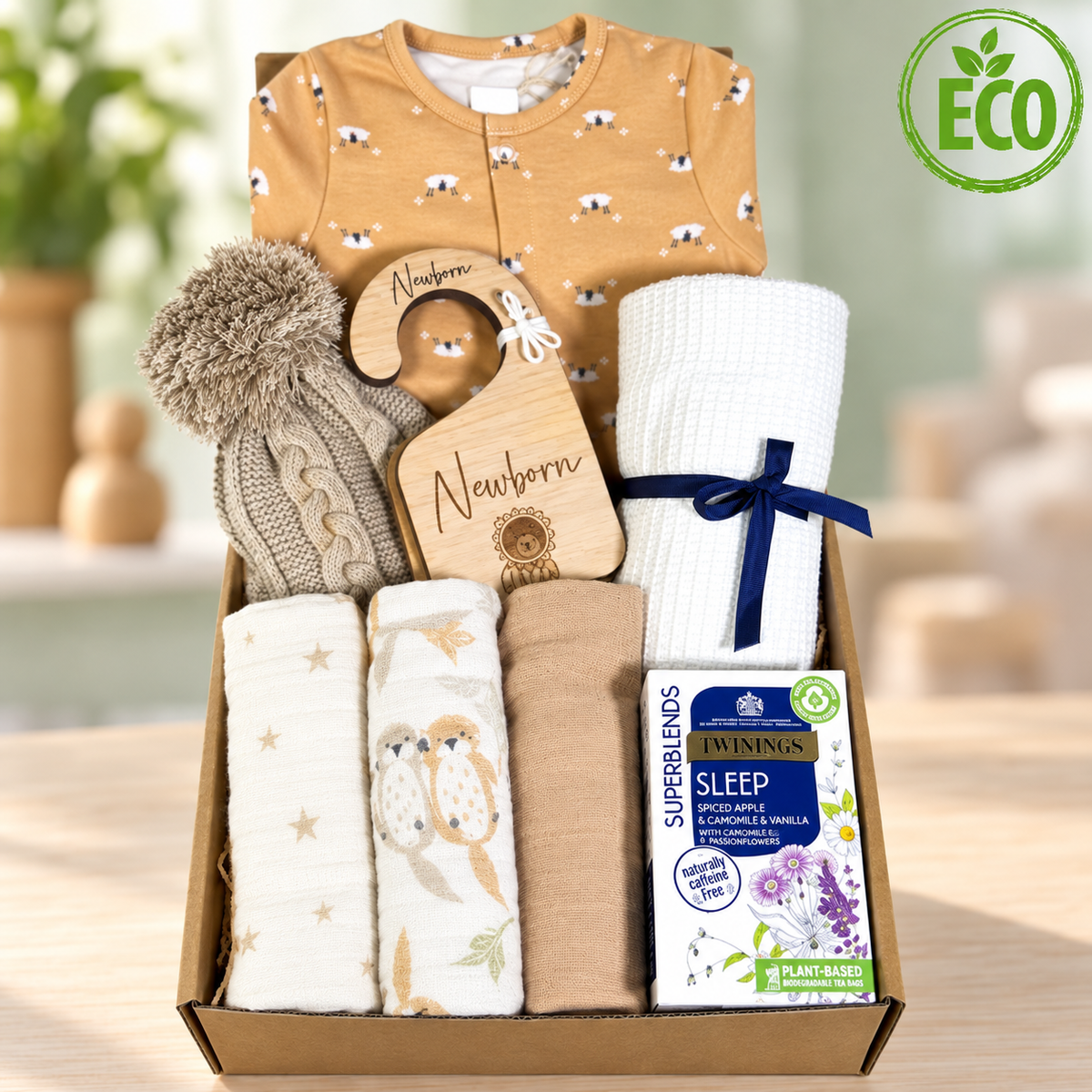 unisex new baby gift of a neutral new baby hamper filled with organic cotton new baby essentials including a otter print sleepsuit and a set of three muslin squares.