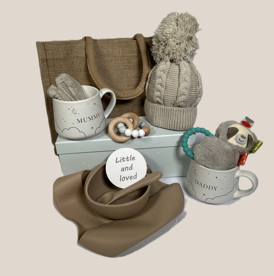 New parents baby hamper with Mummy and daddy mugs, a baby pompom hat, a silicone baby bib, bowl and spoon set
