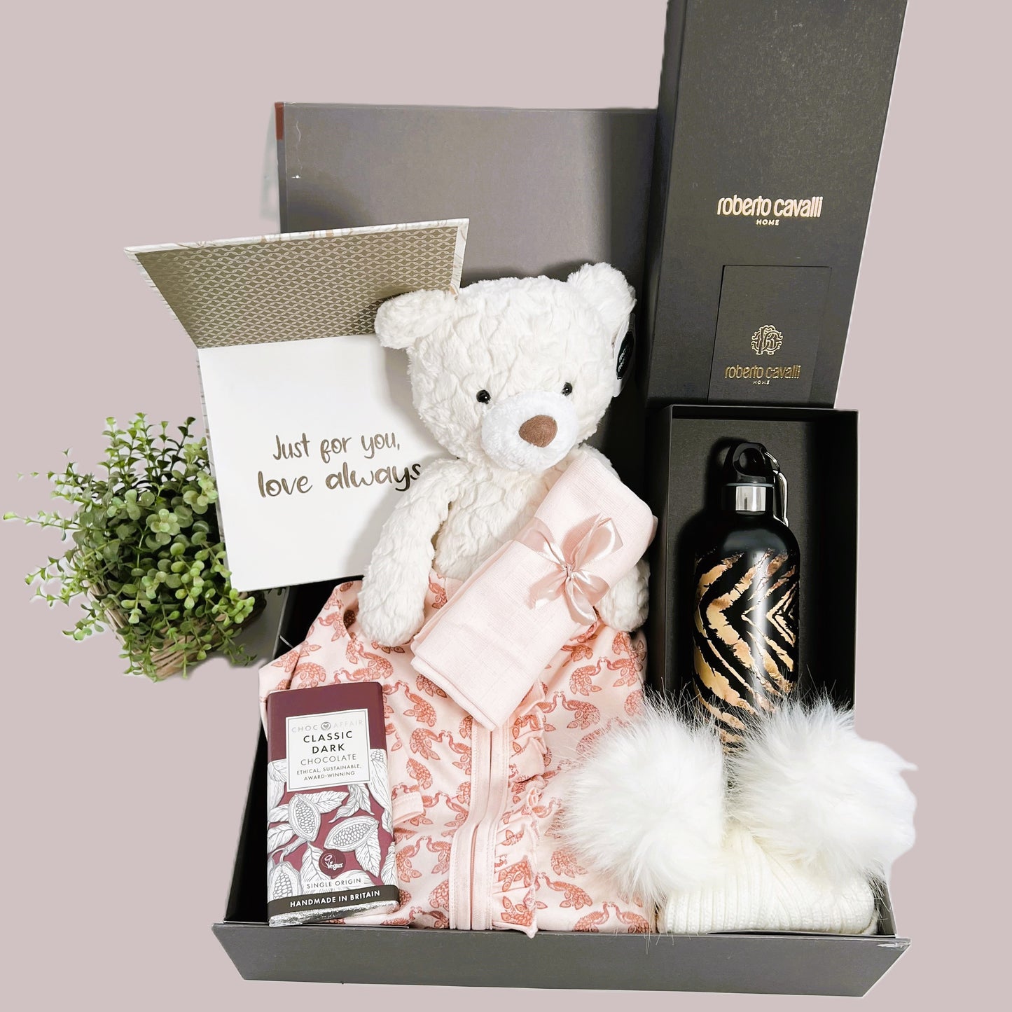 New Parents gift, this baby girl hamper comes in a grey baby keepsake box containing  a Roberto Cavelli wtaer bottle, an organic zipped baby sleepsuit, a Mary Meyer cream Teddy bear, a handcrafted baby journal, a baby pompom hat and a bar of Choc Affair chocolate.