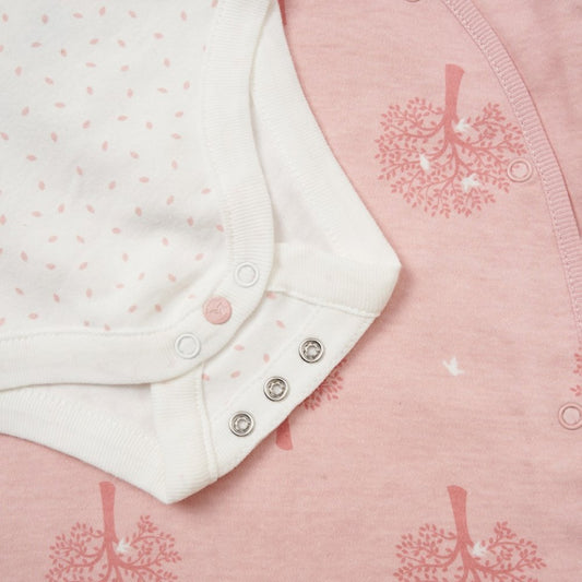 Close-up of baby clothing with pink and white patterns on a pink background