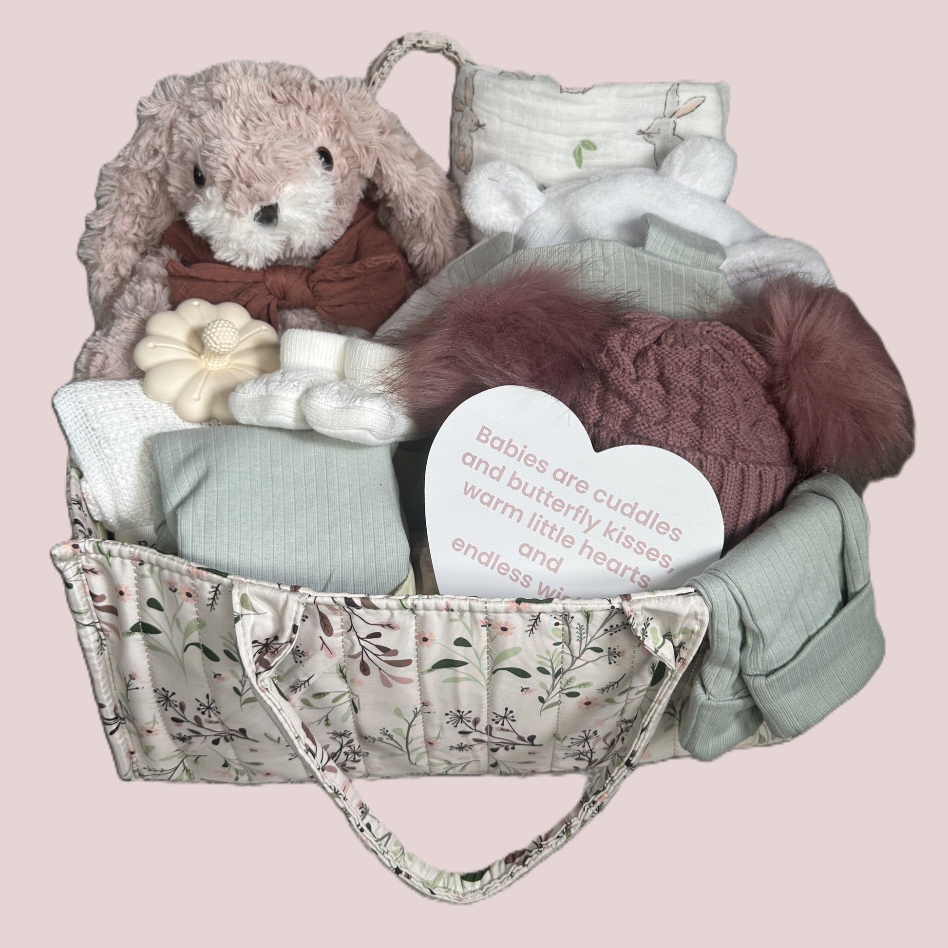 Gift basket with plush toys and baby items on a pink background