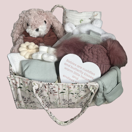Gift basket with plush toys and baby items on a pink background