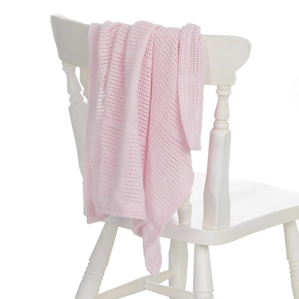 Pink cellular baby blanket draped over a white chair on a white background