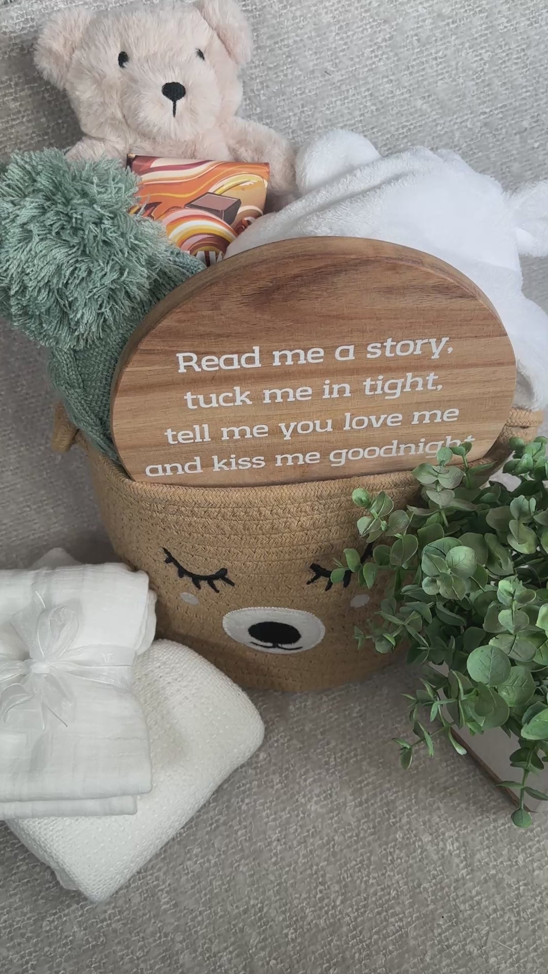 Video of a new baby gift basket, neutral colour palette, bear baby comforter , nursery sign baby dressing gown and chocolate