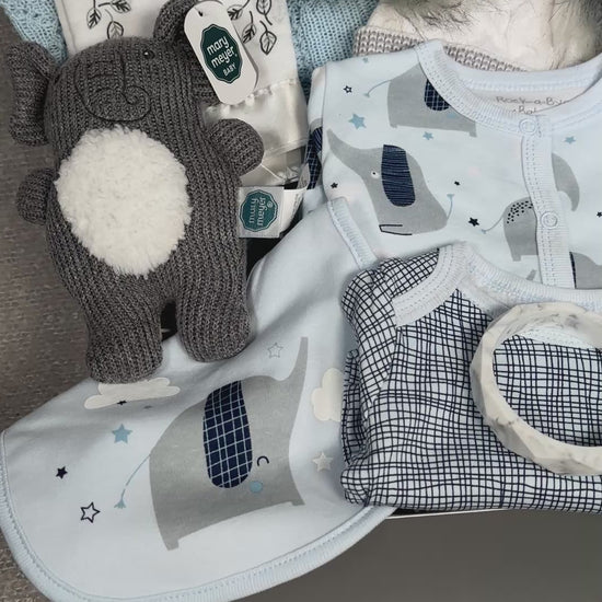 Video of an elephant themed baby hamper with cotton babywear, a baby hat, a blue cotton blanket, a baby rattle and two  security blankets.