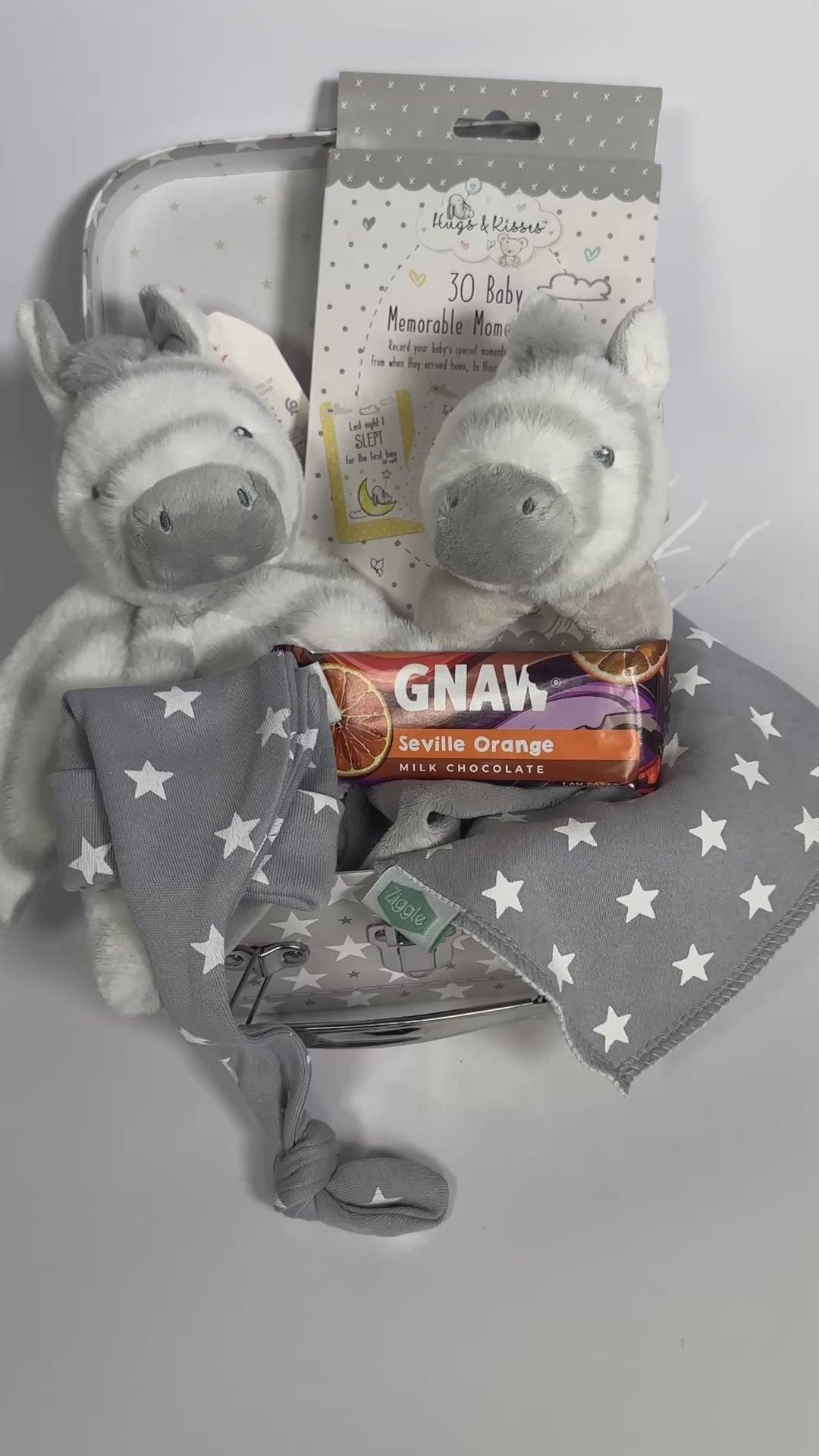 A baby keepsake case with two Keeleco zebra baby toy, a bar of seville orange Gnaw chocolate, a bay knot hat and bib.